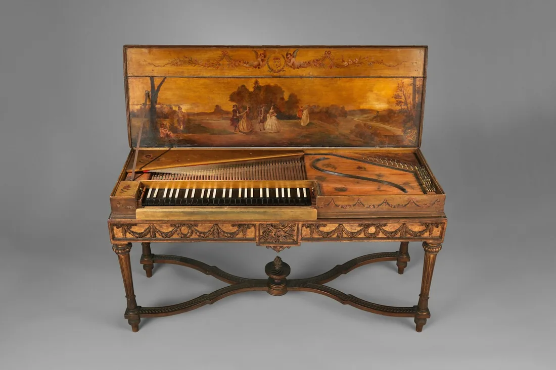 Instrumento histórico de tecla con la tapa levantada, cuerdas a la vista y caja sobre patas torneadas
